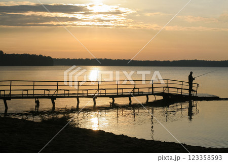 silhouette of a fisherman at sunset on the lake 123358593