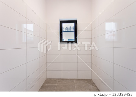 A minimalist room with a large window and tiled walls, creating a clean, calm aesthetic 123359453