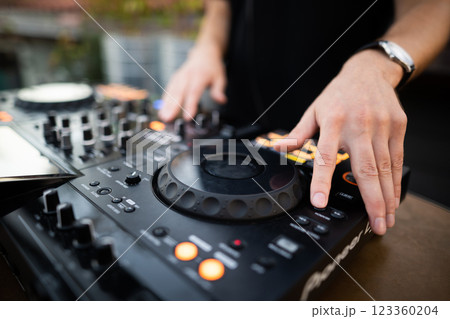 a DJ plays music on a controller at a party a DJ plays music on a controller at a party 123360204