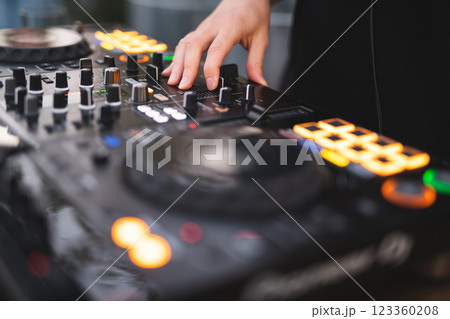 a DJ plays music on a controller at a party 123360208