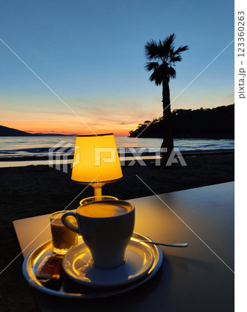 a mug of fragrant coffee on a table on a sea beach at sunset a mug of fragrant coffee on a table on a sea beach at sunset 123360263