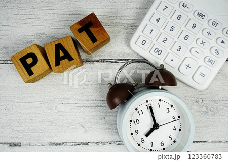 PAT (Profit After Tax) text with alarm clock and calculator on wooden background PAT (Profit After Tax) text with alarm clock and calculator on wooden background 123360783