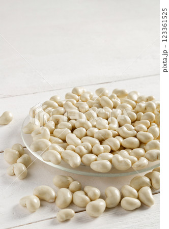 Cashew nuts in milk chocolate on a white wooden background. Cashew nuts in milk chocolate on a white wooden background. 123361525
