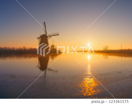 Windmills in the Netherlands during sunrise. Foggy morning and sunshine. Dutch canals. Windmills in the Netherlands during sunrise. Foggy morning and sunshine. Dutch canals. 123361575
