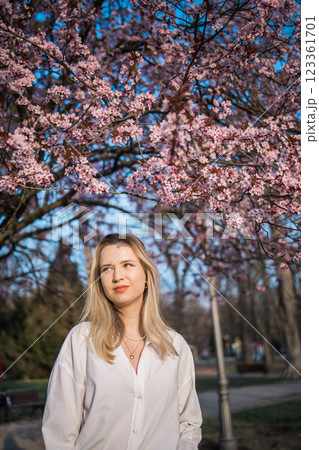 Woman with cherry flowers surrounded by blossoming trees copy space. Beauty and seasonal change and spring bloom season concept. 123361701