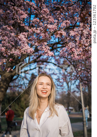Woman with cherry flowers surrounded by blossoming trees copy space. Beauty and seasonal change and spring bloom season concept. 123361702
