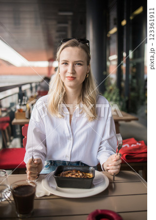 Blonde gen z woman eating lasagna in the cafe on break. Gen z girl spend time in restaurant 123361911