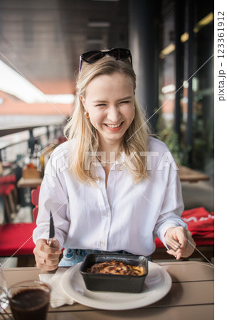 Blonde gen z woman eating lasagna in the cafe on break. Gen z girl spend time in restaurant Blonde gen z woman eating lasagna in the cafe on break. Gen z girl spend time in restaurant 123361912