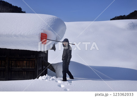 豪雪地帯で雪下ろしをする老人 123362033