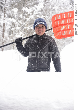 田舎で雪の降る中除雪をしている元気な老人 123362053