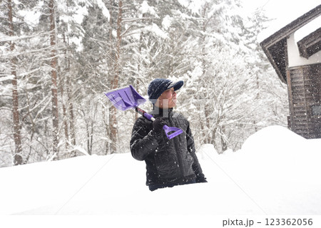 田舎で雪の降る中除雪をしている元気な老人 田舎で雪の降る中除雪をしている元気な老人 123362056