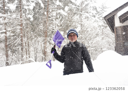 田舎で雪の降る中除雪をしている元気な老人 123362058