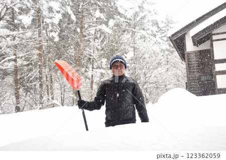 田舎で雪の降る中除雪をしている元気な老人 123362059