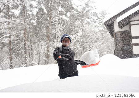 田舎で雪の降る中除雪をしている元気な老人 123362060