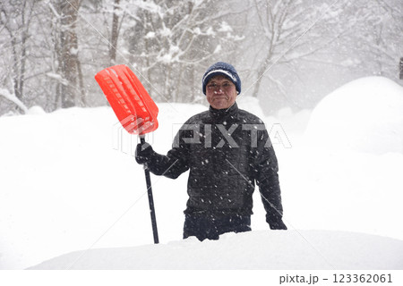田舎で雪の降る中除雪をしている元気な老人 123362061
