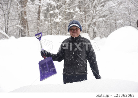 田舎で雪の降る中除雪をしている元気な老人 123362065