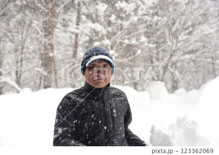 田舎で雪の降る中除雪をしている元気な老人 123362069