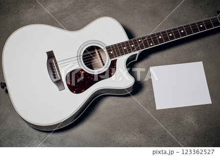 Top View of Acoustic Guitar on Gray Background with Blank Card for Music Concept and Design Top View of Acoustic Guitar on Gray Background with Blank Card for Music Concept and Design 123362527