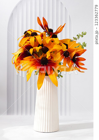 Beautiful still life with rudbeckia bouquet on light elegant table, autumn banner, abstract floral arrangement, rustic style, holiday card and screen template, selective focus. 123362779
