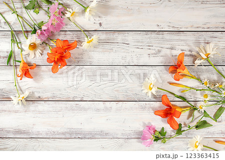 Flowers of lilies, daisies and hollyhocks on an old wooden background, summer and autumn banner for product advertising, abstract floral arrangement, rustic style, holiday card, selective focus. Flowers of lilies, daisies and hollyhocks on an old wooden background, summer and autumn banner for product advertising, abstract floral arrangement, rustic style, holiday card, selective focus. 123363415