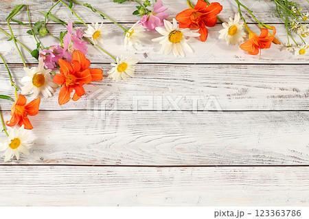 Flowers of lilies, daisies and hollyhocks on an old wooden background, summer and autumn banner for product advertising, abstract floral arrangement, rustic style, holiday card, selective focus. Flowers of lilies, daisies and hollyhocks on an old wooden background, summer and autumn banner for product advertising, abstract floral arrangement, rustic style, holiday card, selective focus. 123363786