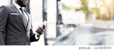 Business Communication. Stylish Afro Businessman Using Cellphone Walking Outdoor. Cropped, Free Space Business Communication. Stylish Afro Businessman Using Cellphone Walking Outdoor. Cropped, Free Space 123364554