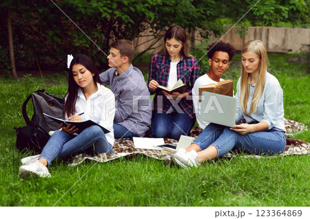 Group of students studying in college campus, using laptop and reading books, preparing for classes 123364869