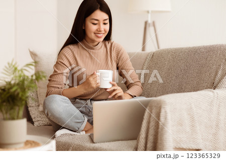 Happy Girl Relaxing on Comfortable Couch and Using Laptop at Home, Surfing Internet Happy Girl Relaxing on Comfortable Couch and Using Laptop at Home, Surfing Internet 123365329