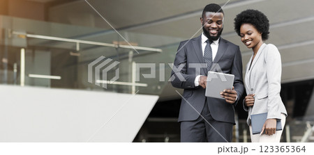 Two cheerful coworkers browsing internet on digital tablet outdoors during break Two cheerful coworkers browsing internet on digital tablet outdoors during break 123365364