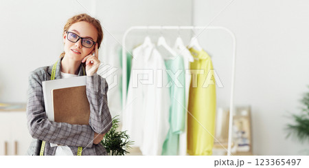 Young clothing designer in own fashion studio, posing to camera and smiling Young clothing designer in own fashion studio, posing to camera and smiling 123365497