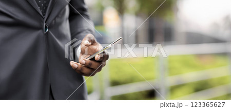 Busy businessman using smartphone browsing internet and drinking take-out coffee outdoors, closeup Busy businessman using smartphone browsing internet and drinking take-out coffee outdoors, closeup 123365627