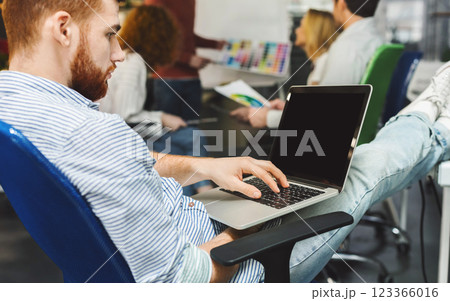 Focused millennial man browsing on laptop with blank screen in modern office, free space Focused millennial man browsing on laptop with blank screen in modern office, free space 123366016