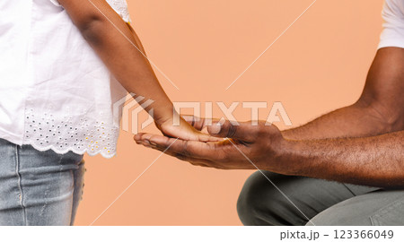 A little girl with brown skin reaches out to an adult males open hand, extending her hand towards him. The man is seated, wearing grey pants and a white shirt, cropped A little girl with brown skin reaches out to an adult males open hand, extending her hand towards him. The man is seated, wearing grey pants and a white shirt, cropped 123366049