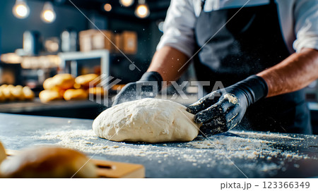 A person kneading dough on a table in a bakery 123366349