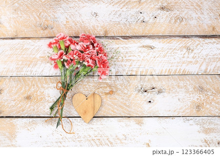 Carnations on a wooden table, abstract spring floral background. Creative modern bouquet, minimal holiday concept. Postcard for womens day or mothers day, happy birthday, wedding, banner for the 123366405