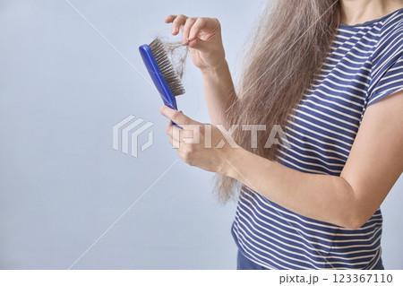 Faceless woman cleans her comb after copious hair loss. Copy space Faceless woman cleans her comb after copious hair loss. Copy space 123367110