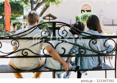 Unfaithful couple holding hands on a park bench, Cheating girlfriend with her boyfriend holding another man's hand in a park. love triangle concept 123367592