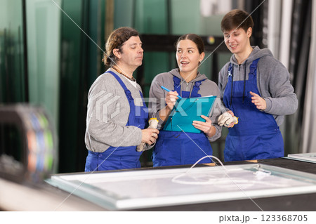 Two men and woman with folder discuss work at glass factory 123368705