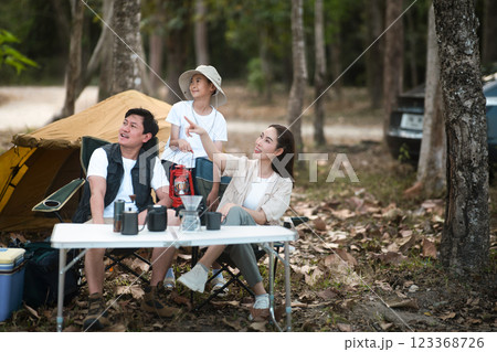 The family of three, Mother and father with a son, go camping in the forest. Mother is pointing away 123368726