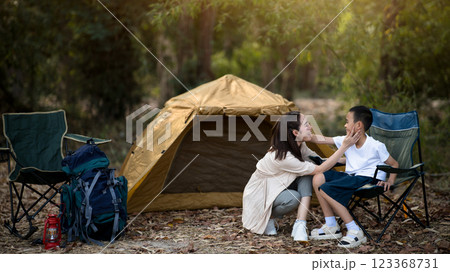 The smiling mother is touching her son face in front of the camping tent. 123368731