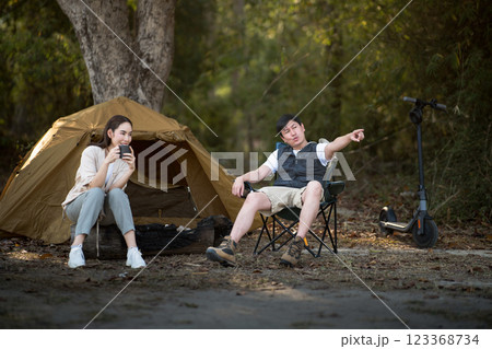 A woman and a man are talking in front of the camping tent. Going camping in the forest. A woman and a man are talking in front of the camping tent. Going camping in the forest. 123368734