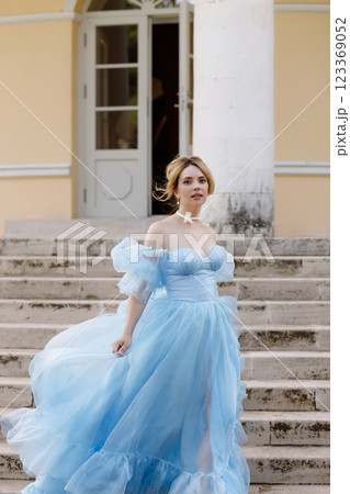 Elegant Woman in a Flowing Blue Gown Walking Down the old stone Stairs 123369052