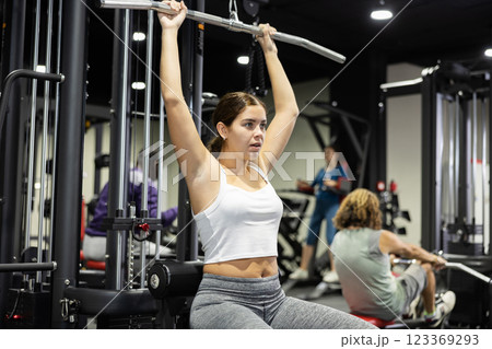 Woman is engaged in a simulator for development of back muscles Woman is engaged in a simulator for development of back muscles 123369293