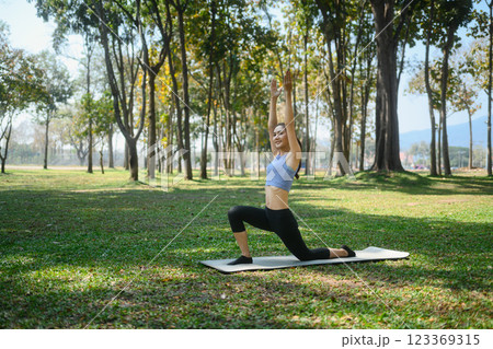 Smiling young woman practicing yoga in a peaceful park 123369315