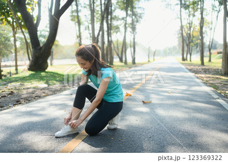 Sporty young woman tying her shoelaces prepares for an outdoor run. Sporty young woman tying her shoelaces prepares for an outdoor run. 123369322