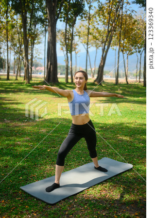Portrait of young man practicing yoga in the park standing in Warrior Two 123369340