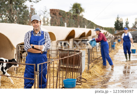 Adult male farmer giving water to calves on farm Adult male farmer giving water to calves on farm 123369397
