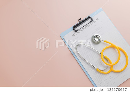 Doctor Day highlights a clipboard with a medical history form and yellow stethoscope on pink Doctor Day highlights a clipboard with a medical history form and yellow stethoscope on pink 123370637