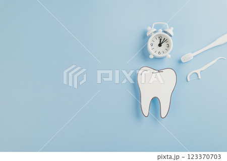 Dentist Day concept. A blue background featuring a paper tooth, dental tools, and a white clock Dentist Day concept. A blue background featuring a paper tooth, dental tools, and a white clock 123370703