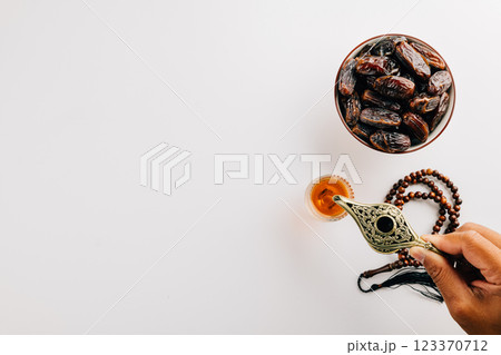 Ramadan flat lay with tea, dates, and prayer beads on a white background. 123370712